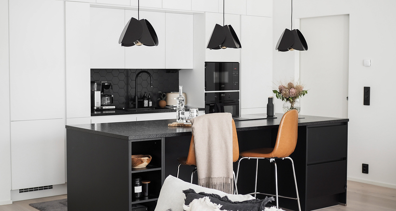 Mustavalkoinen keittiö, jossa kolme mustaa Sessak Lehmus -valaisinta.