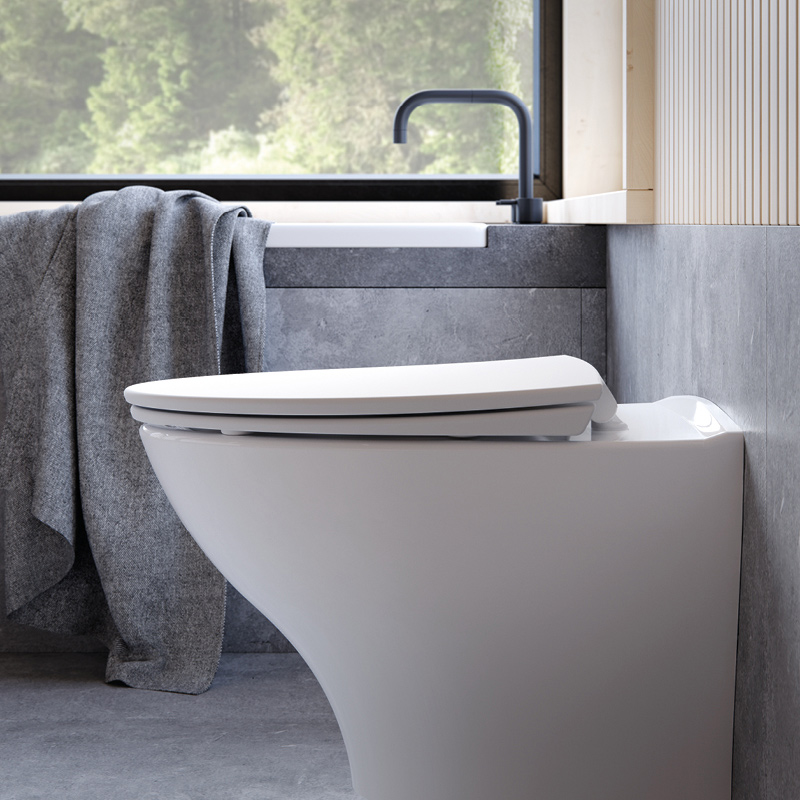 Moderni kylpyhuone: valkoinen seinäkiinnitteinen WC, harmaa pyyhe, musta hana ja ikkuna.