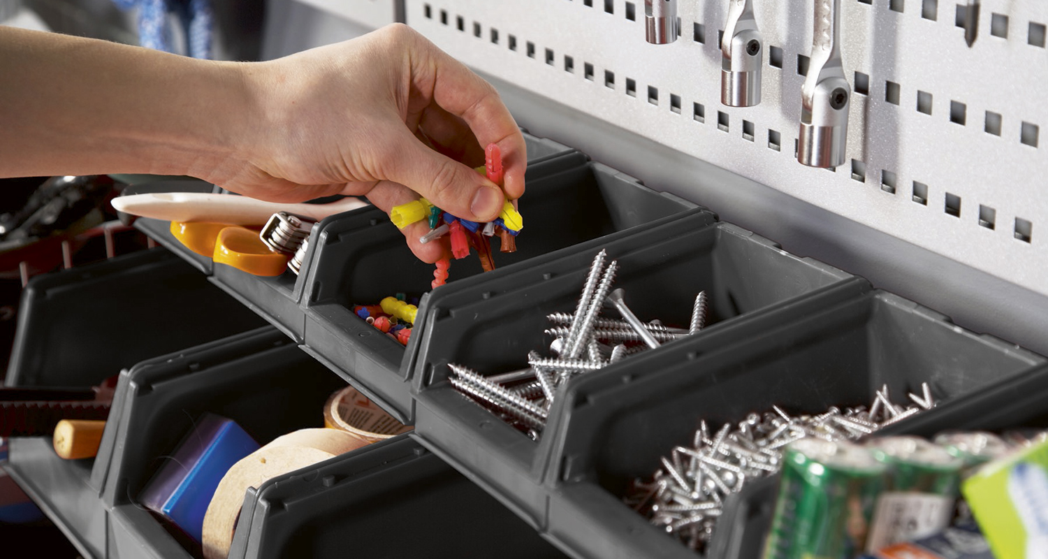 Käsi poimii värikkäitä muuriankkureita mustasta muovilokerikosta, vieressä hopearuuvit