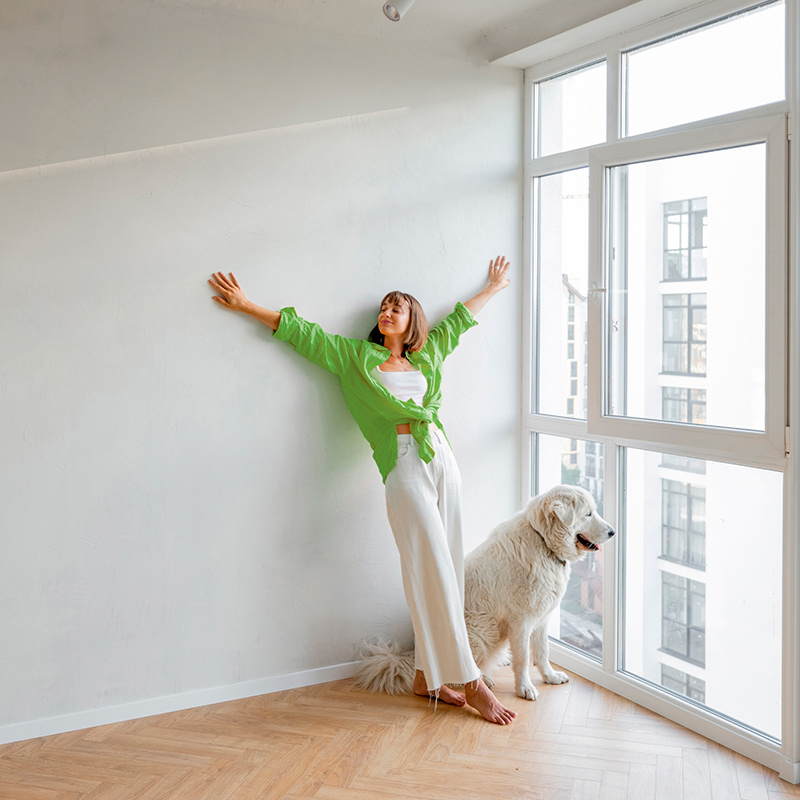 Nainen vaaleassa asunnossa koiran kanssa