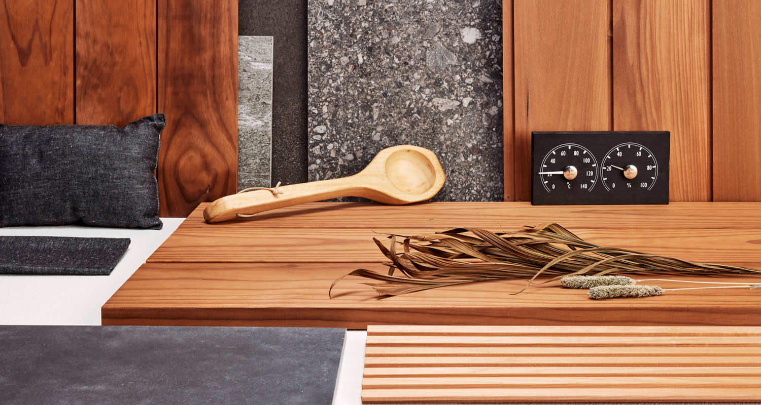 Kuvassa tummia pintamateriaaleja saunaan sekä saunatarvikkeita.