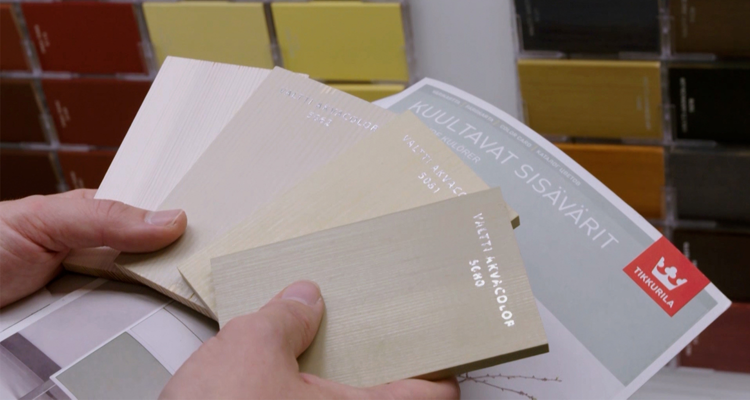 Kädet pitävät Tikkurilan vaaleiden neutraalien sisämaalisävyjen värikortteja.