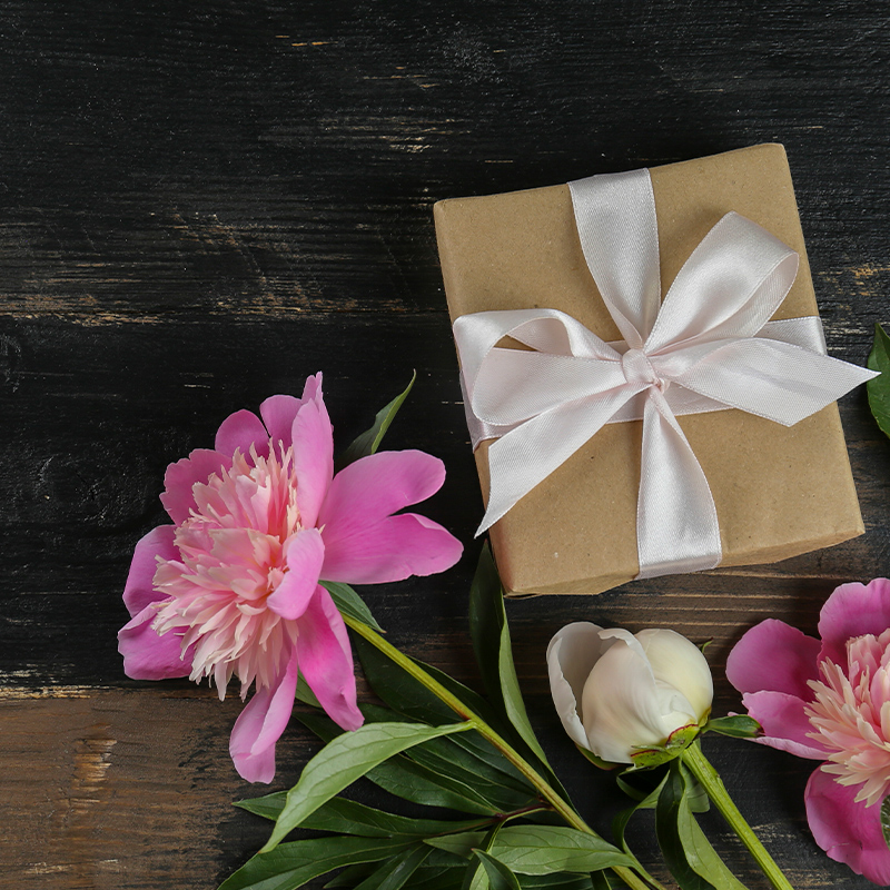 Lahjaideat: Kuvassa lahja sekä kukkia