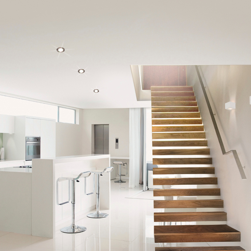 Moderni avokeittiö valkoisilla työtasoilla kromibaarituolit ja kelluvat puuportaat