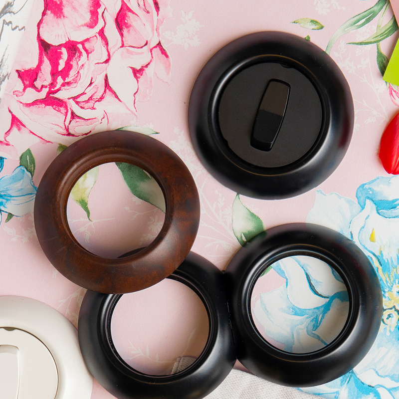 Erikokoisia puunvärisiä, mustia ja valkoisia verholenkkejä vaaleanpunaisella kukkapohjalla.