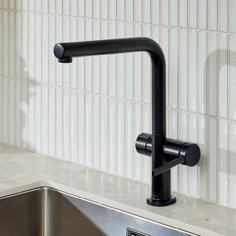 Musta kulmikas keittiöhana vaalean kivitasotason ja valkoisten pystylaattojen edessä