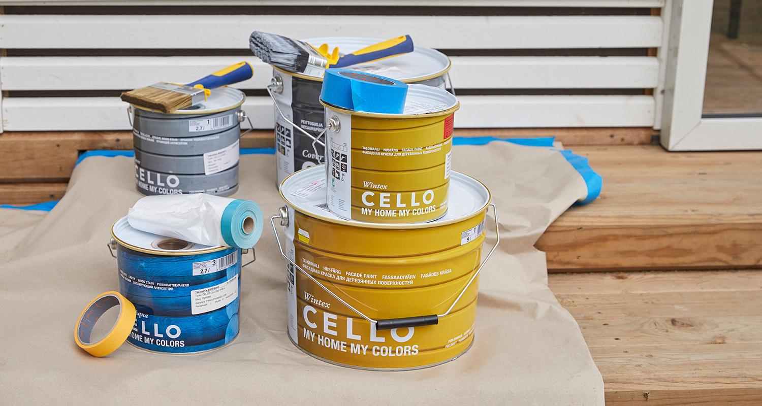 Puisella terassilla keltaisia ja sinisiä Cello-maalipurkkeja, siveltimiä ja teippiä.