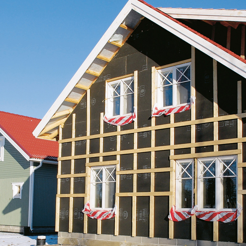 Rakenteilla oleva puutalo mustalla ulkoverhouksella, puuristikolla ja valkoisilla ikkunoilla