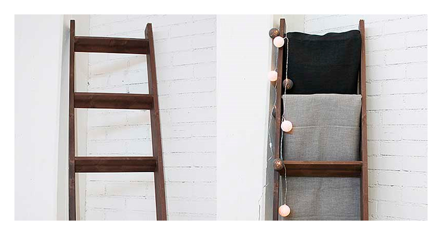 Ruskeat puutikkaat valkoista tiiliseinää vasten; oikealla musta ja harmaa viltti, pallovalot.