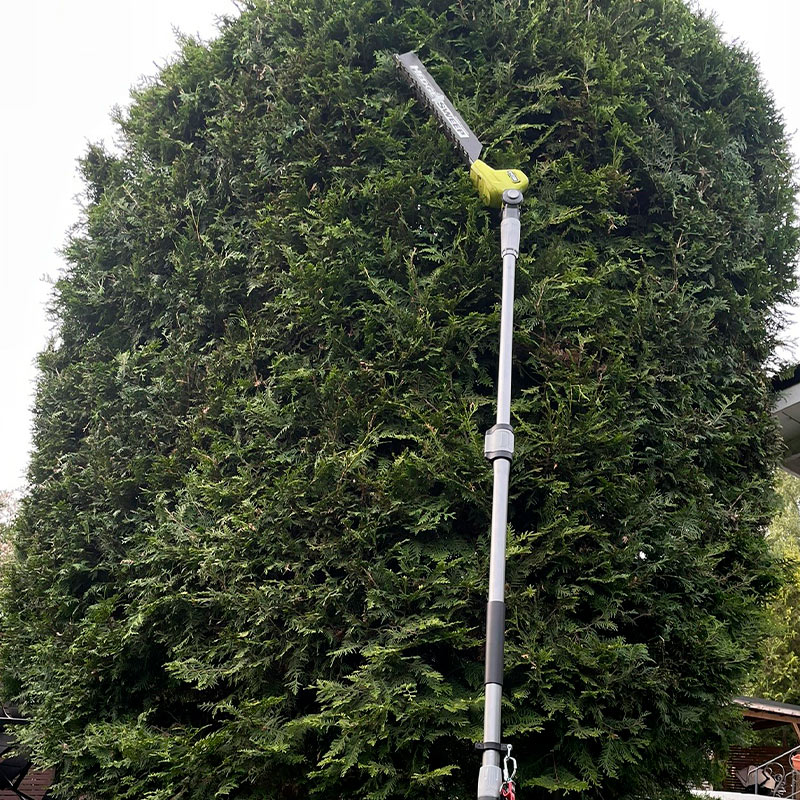 Ryobi RY18PHT40A-0 18V ONE+ -akkupensasleikkuri teleskooppivarrella apuna korkeiden tuijien muotoilussa.