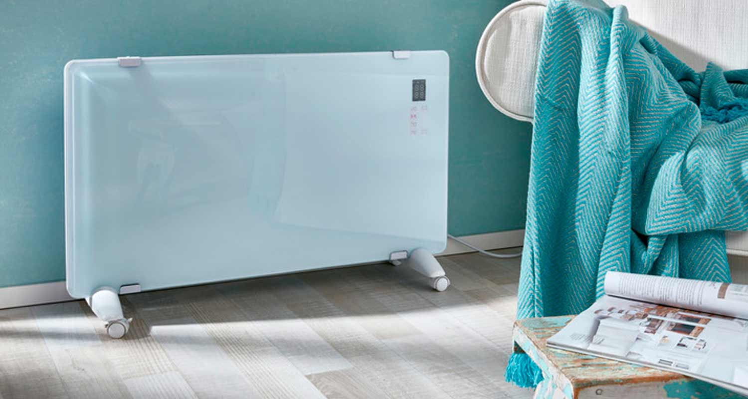 Valkoinen lasipaneelilämmitin rullajaloilla, turkoosi huopa ja avoin lehti jakkaralla