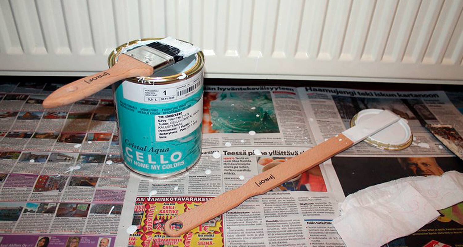 Turkoosi Cello-maalipurkki ja valkoinen sivellin sanomalehden peitossa patterin edessä.