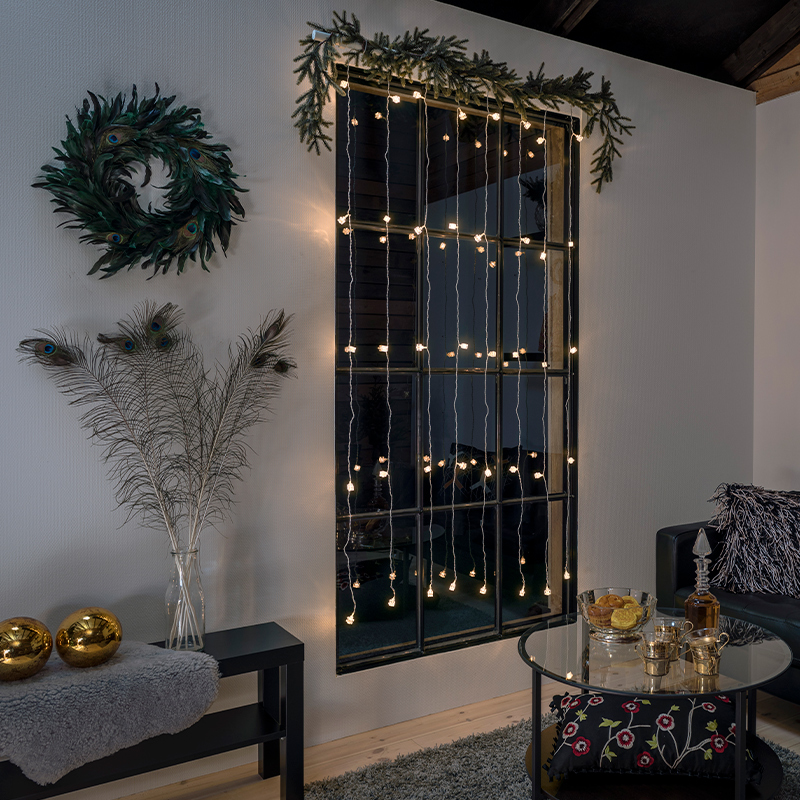 Valoverhot olohuoneen ikkunassa. Olohuone on sisustettu joulukoristeilla.