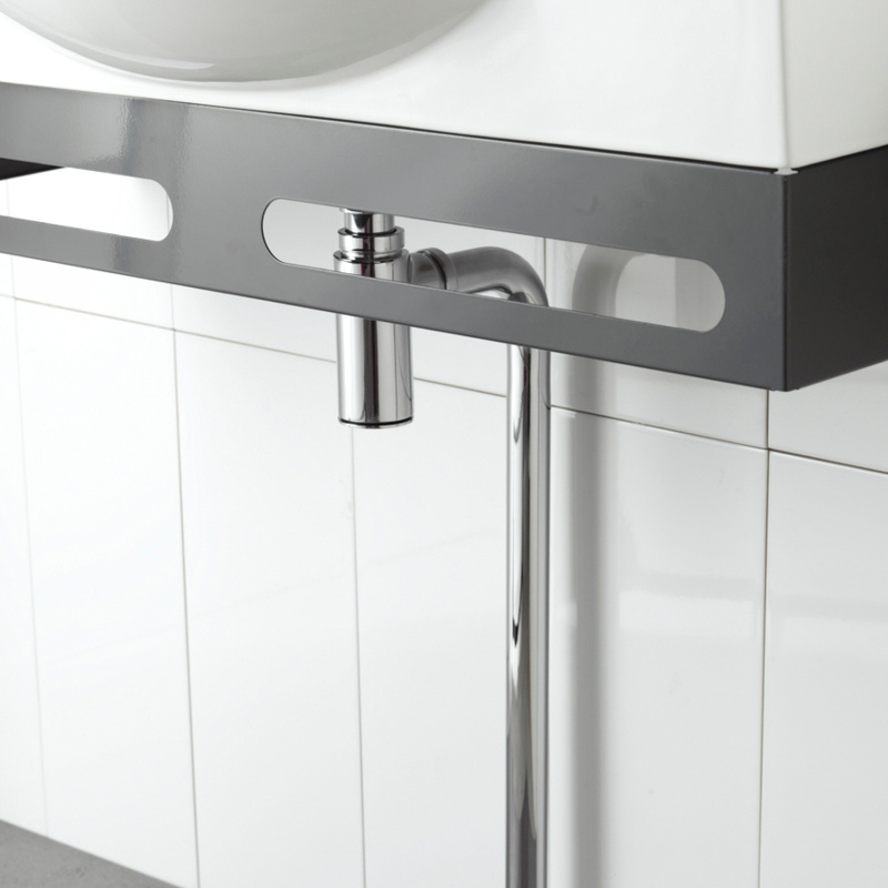 Valkoisen altaan alla harmaa metalliteline ja krominen viemäriputki valkoista laattaa vasten