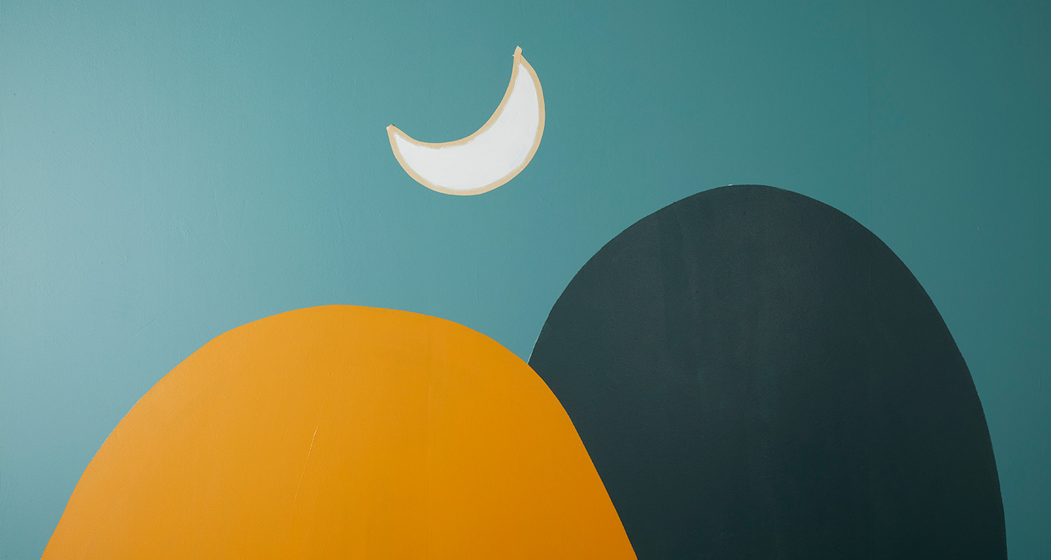 Turkoosilla seinällä abstrakti maalaus: oranssi kumpare, tummanharmaa kumpare ja valkoinen puolikuu.