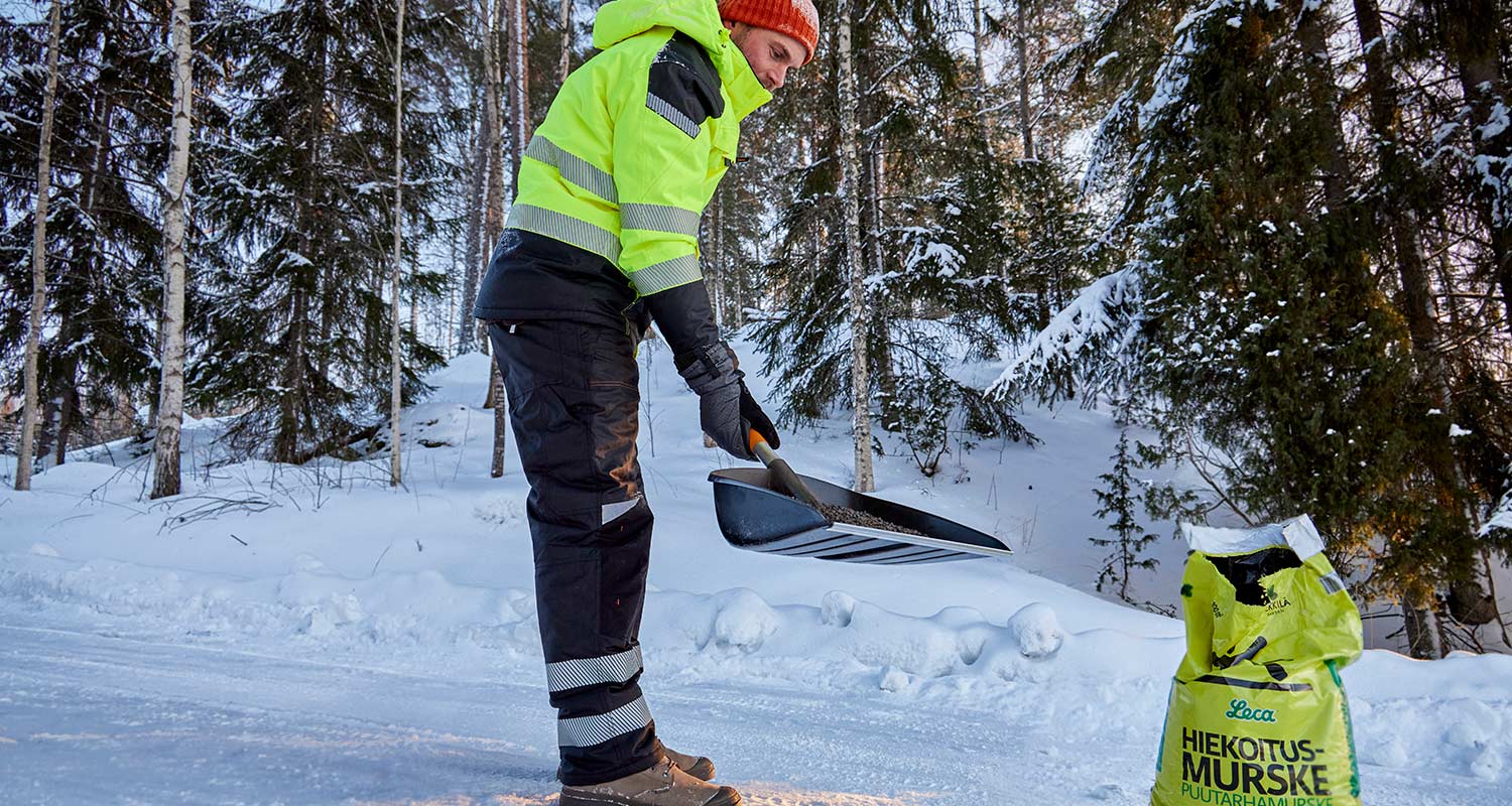 Mies hiekoittaa tietä talvella päällään lämpimät ja näkyvät työvaatteet, jotka löytyvät K-Raudasta