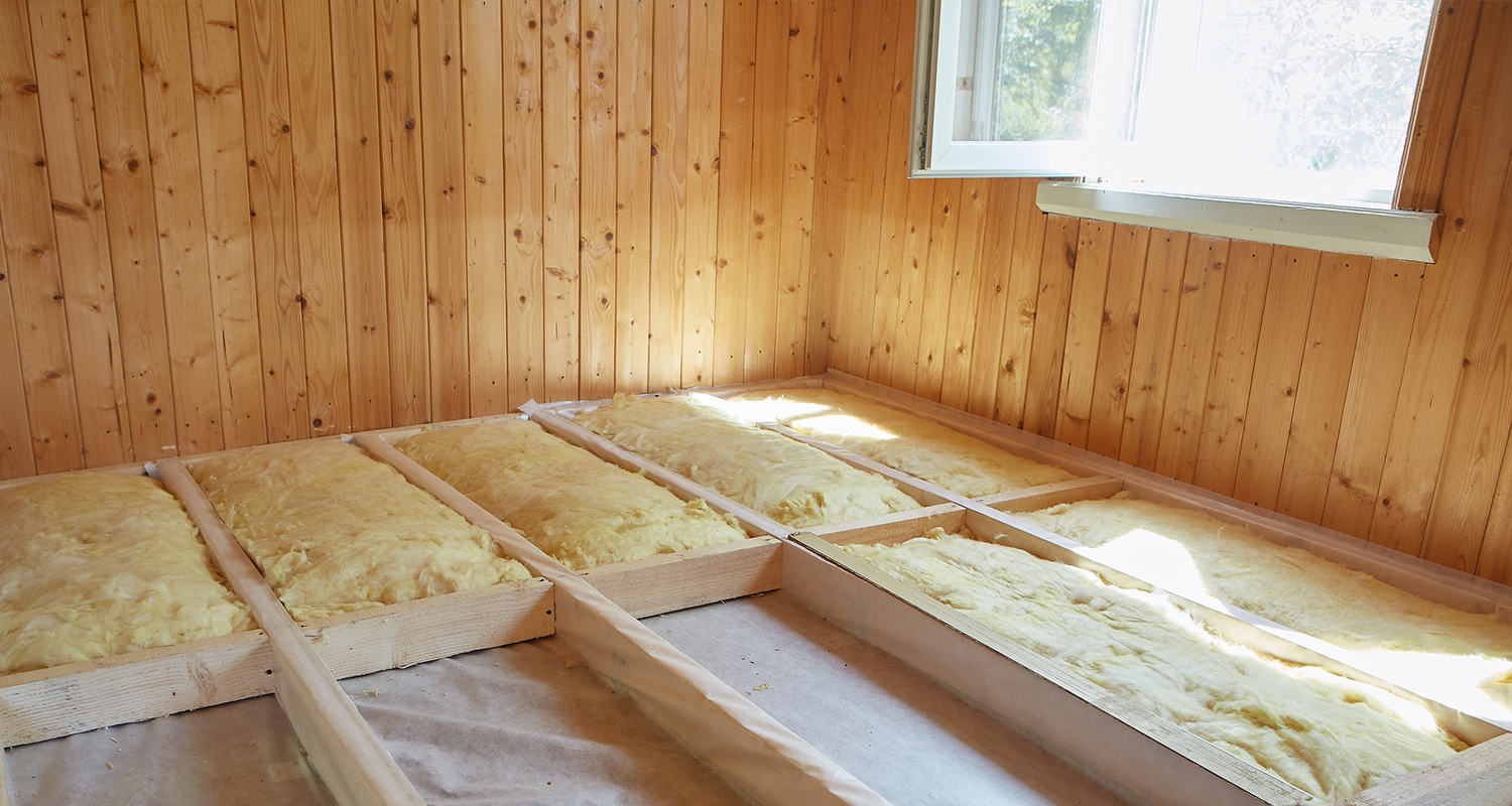 Puisen paneelihuoneen lattiarakenteessa keltaista villaeristettä auringonvalossa