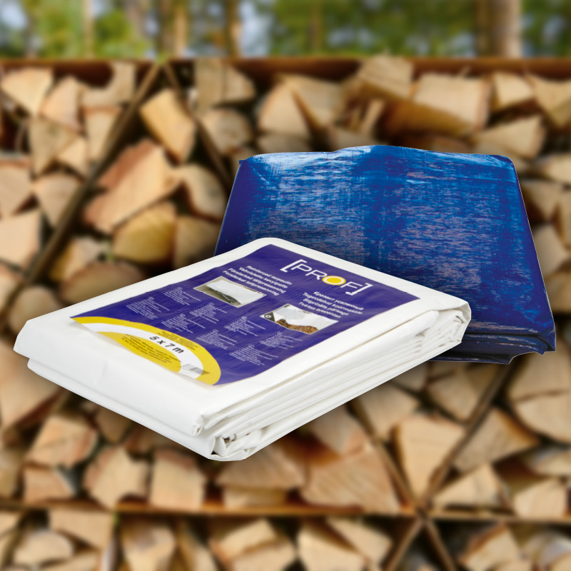 Valkoinen PROFI-suojapeite ja sininen pressu polttopuun kasan edessä.