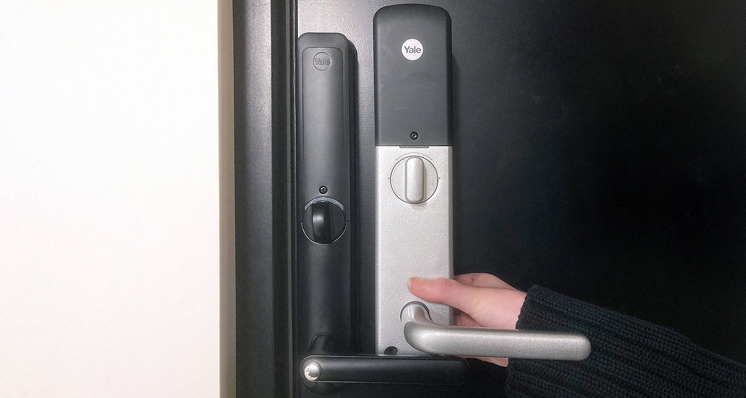 Kuvassa ulko-oveen asennettu siro älylukko Yale Doorman L3 musta sekä kaksivärinen vanhempi malli
