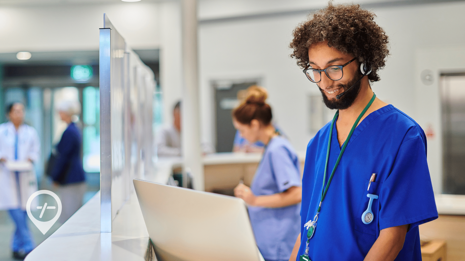 A male nurse works on a computer at the nurses' desk inside a hospital.