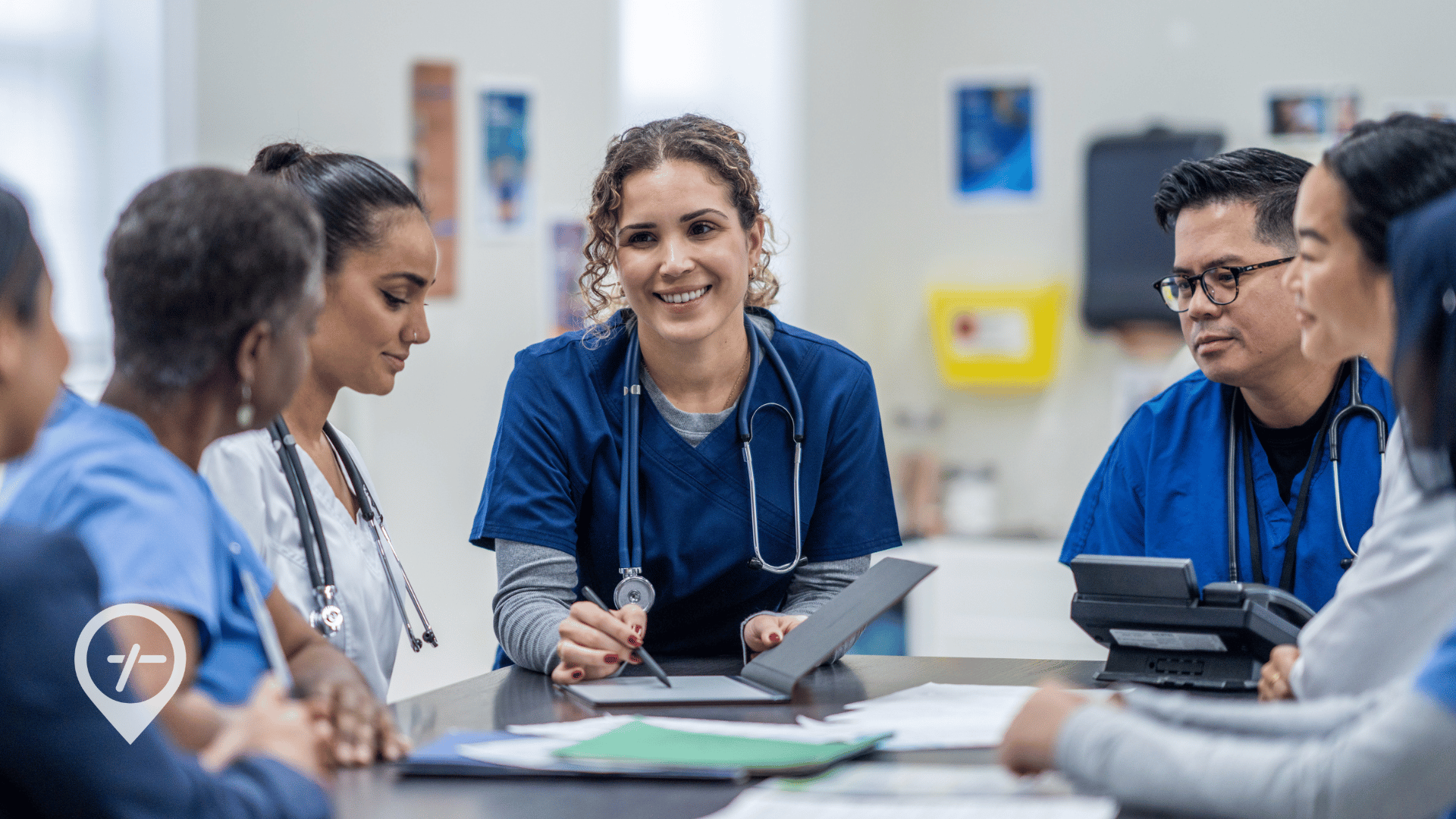 A group of hospital nurses sit around a table discussing shift fulfillment.