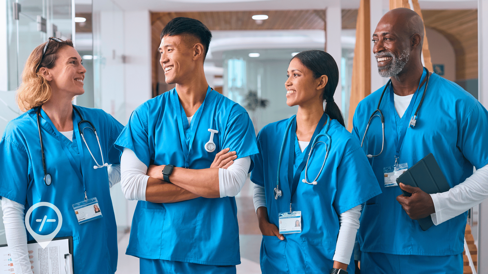 A group of nurses is standing in a hospital hallway, smiling and talking.