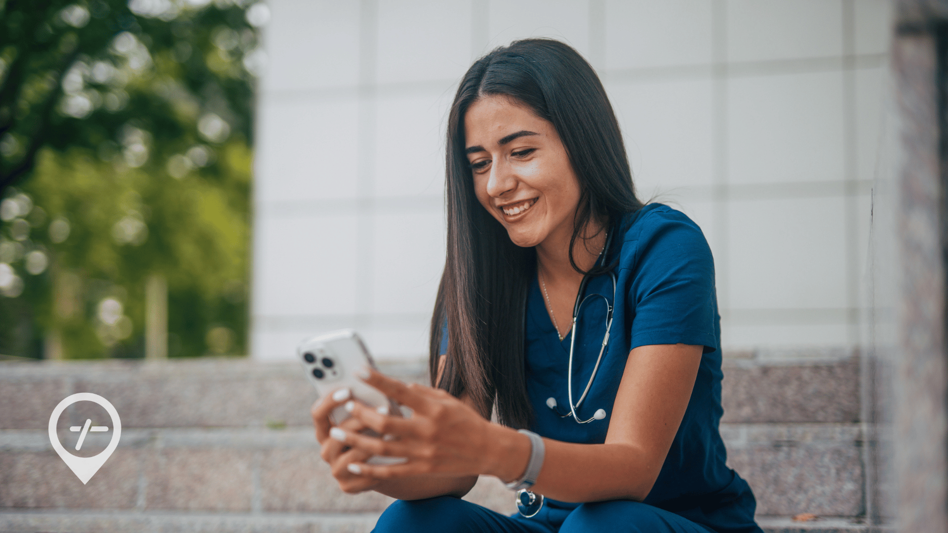 A registered nurse sitting outside a hospital using a nursing jobs app on her smartphone to find flexible RN shifts.
