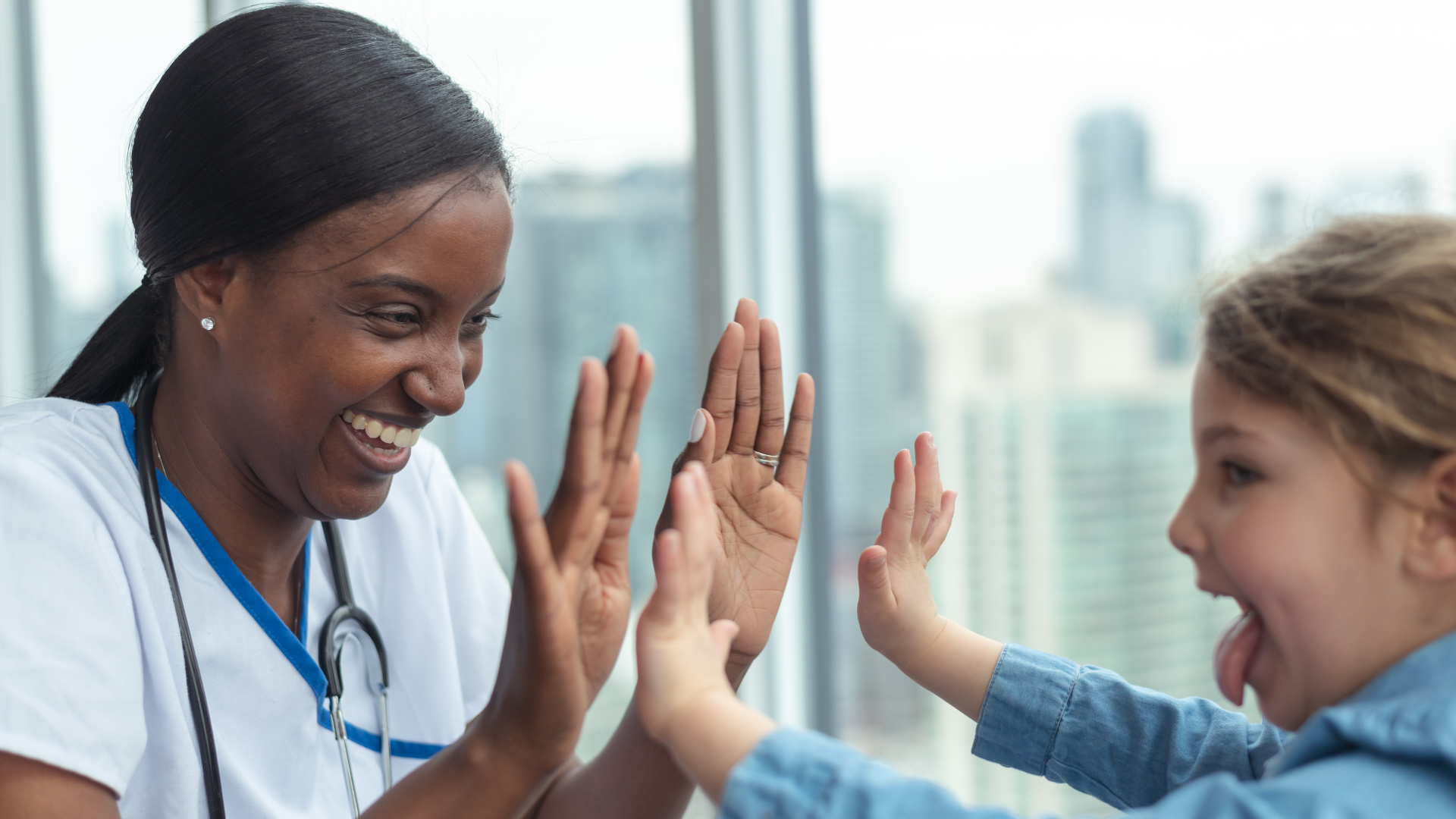 A nurse gives a child patient high fives.