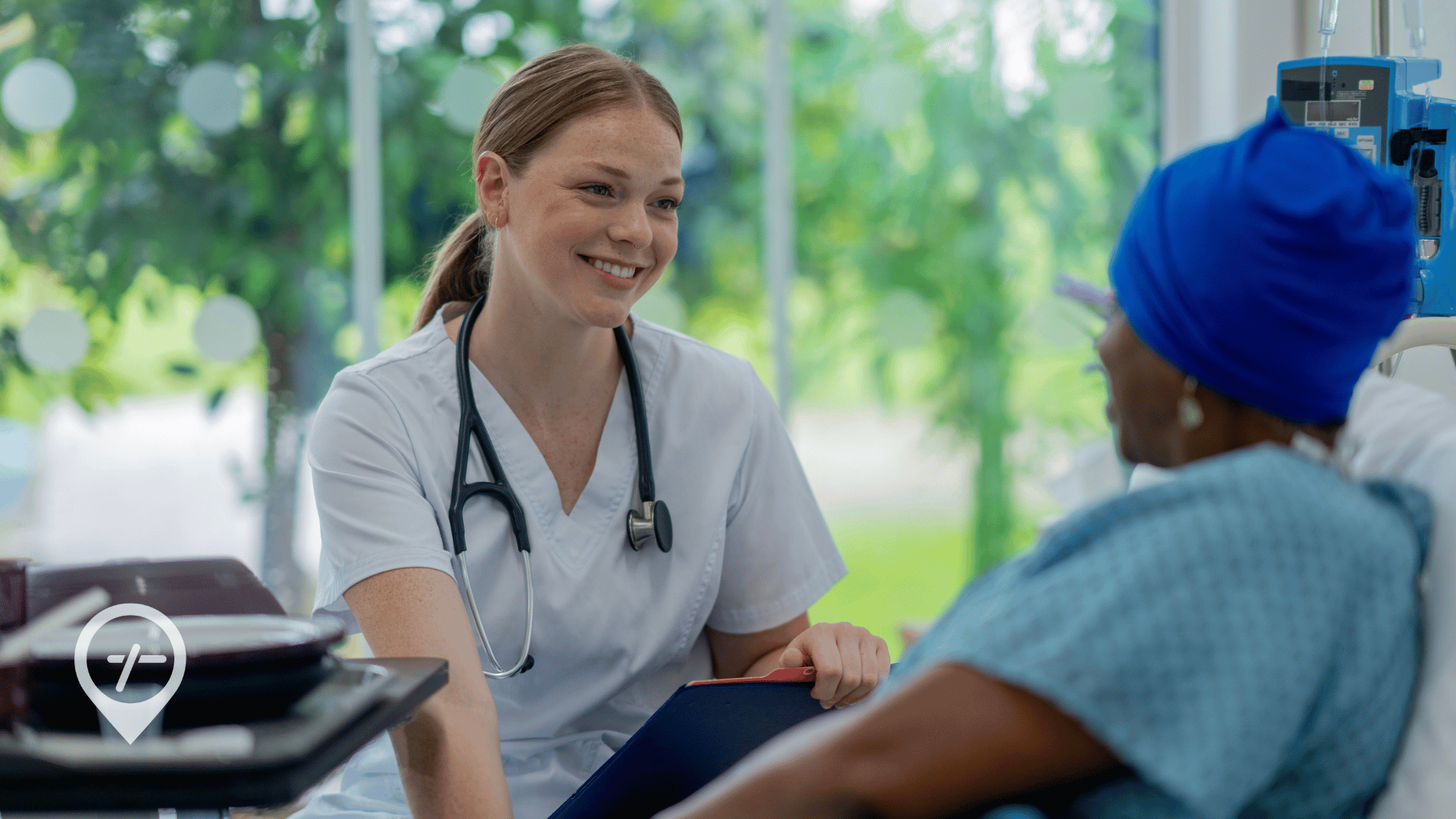A nurse smiles while sitting with a patient in a long-term care facility.