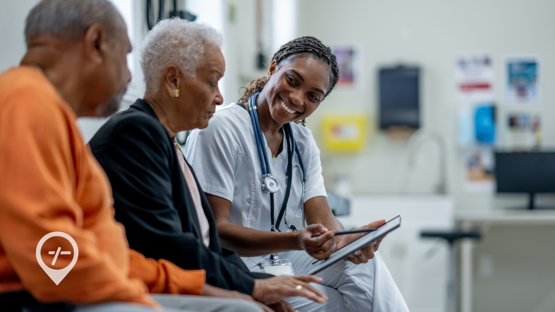 An image of a nurse sitting down with two elderly patients inside a hospital.
