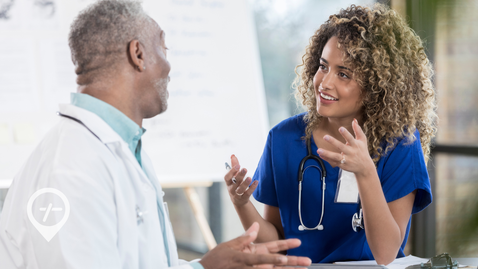 A nurse is sitting down with a doctor discussing patient care.