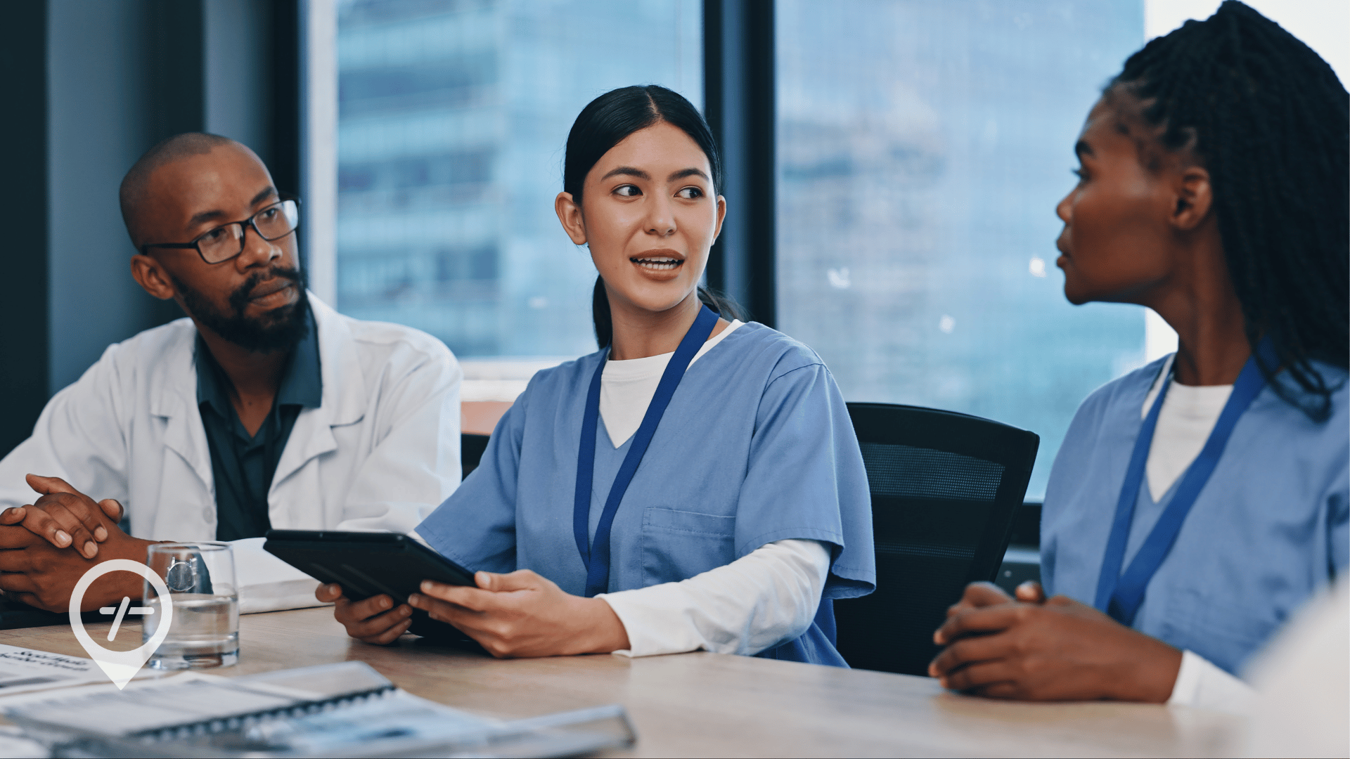 Two nurses and a doctor discussing patient care and hospital staffing strategy in a conference room, illustrating collaborative healthcare workforce management.
