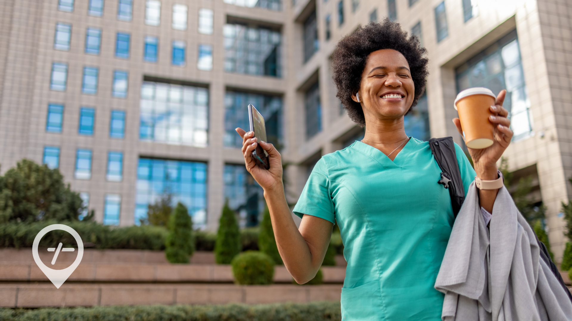 A nurse leaves work with a coffee in hand and a smile on her face. 