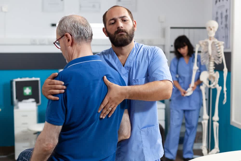 Orthopedic nurse helping a patient with his posture