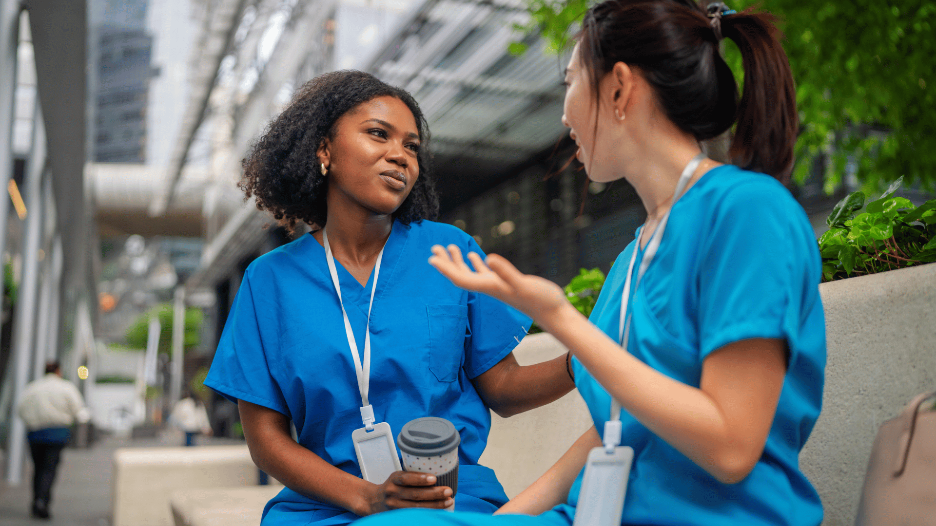 Two nurses talking outside a hospital during a break, illustrating nurse work-life balance and strategies to reduce nurse turnover.