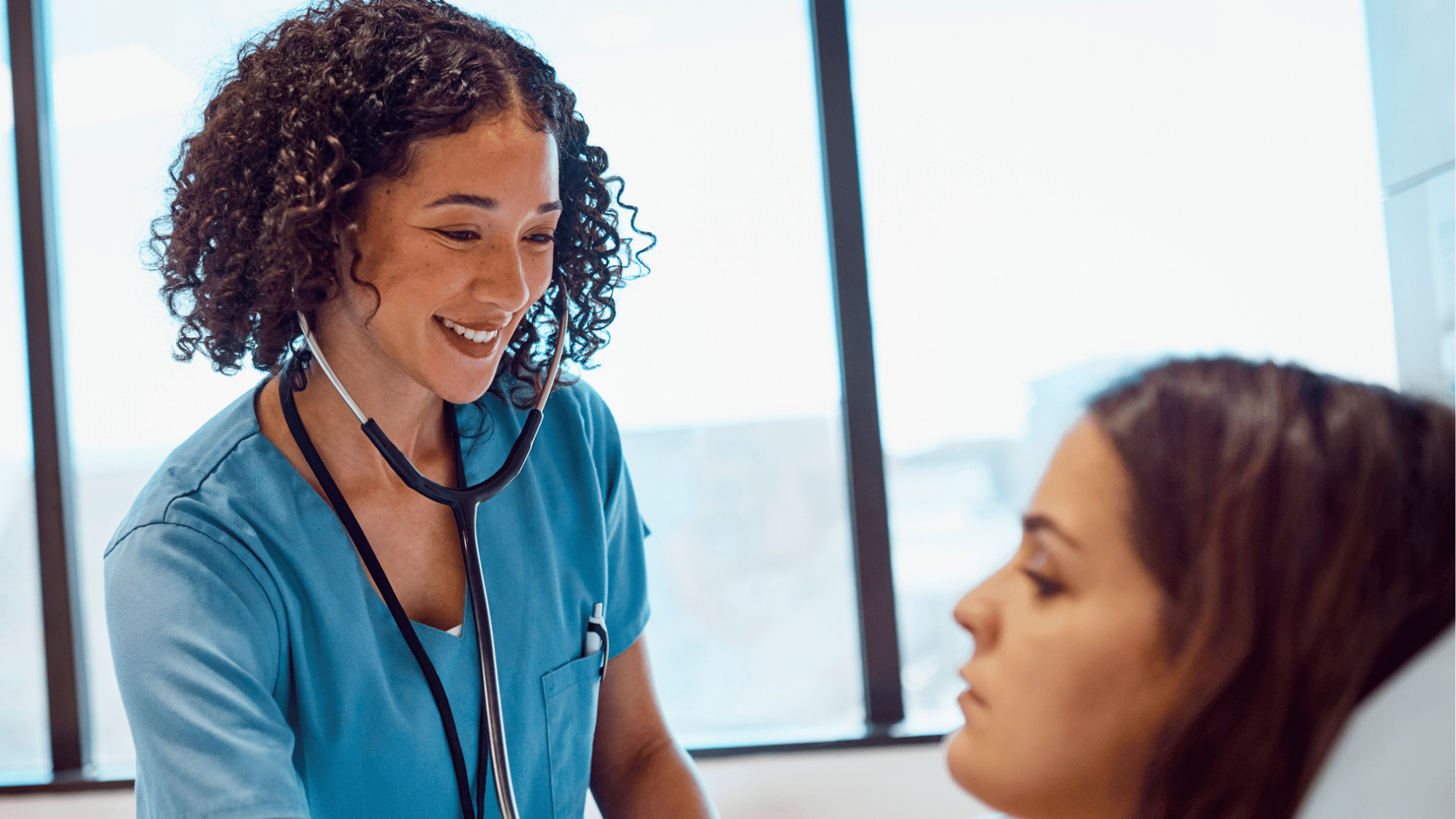 A young nurse attends to a patient at the bedside. 