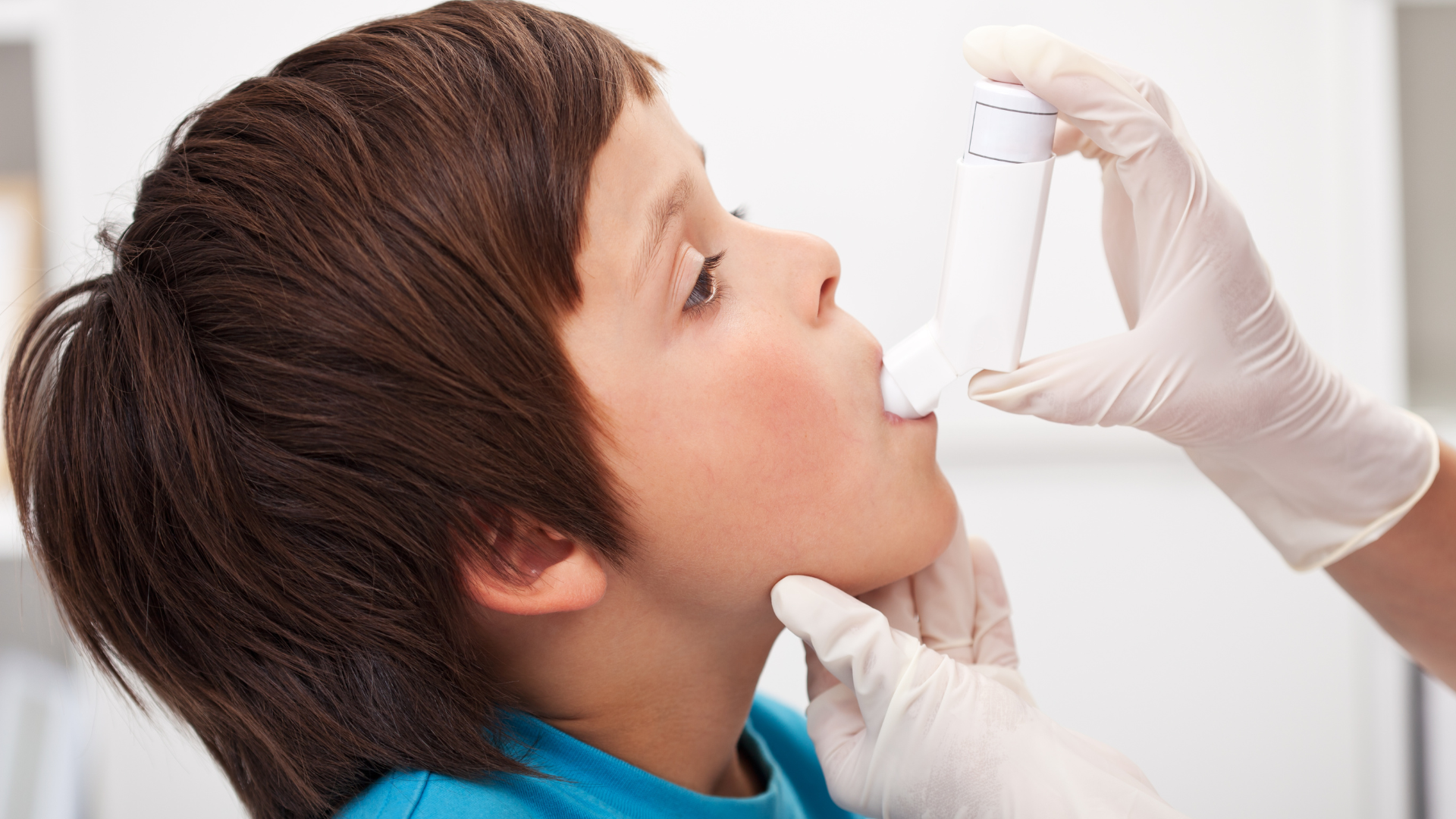A respiratory therapist administers an inhaler to a young boy.  