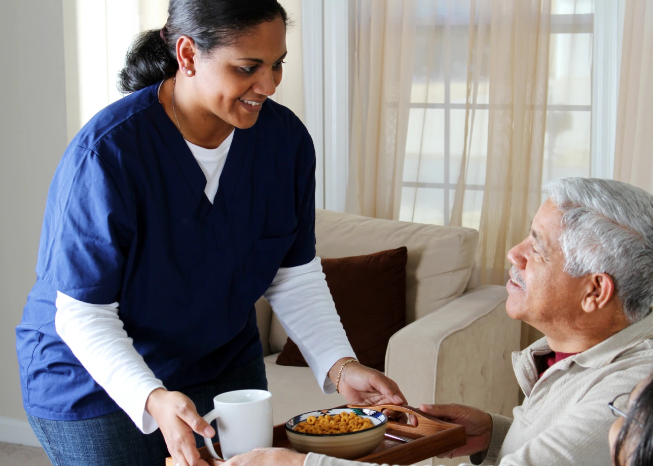 LatinX female STNA assists elderly patient at home.