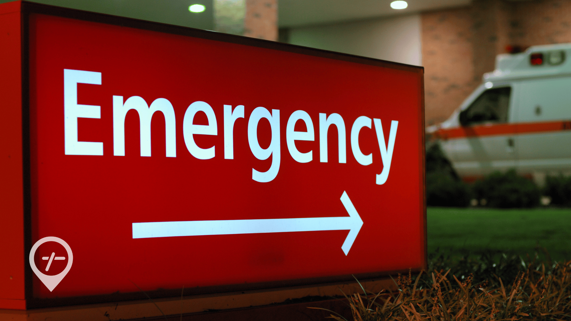 Emergency room sign outside of a hospital with an ambulance in the background.