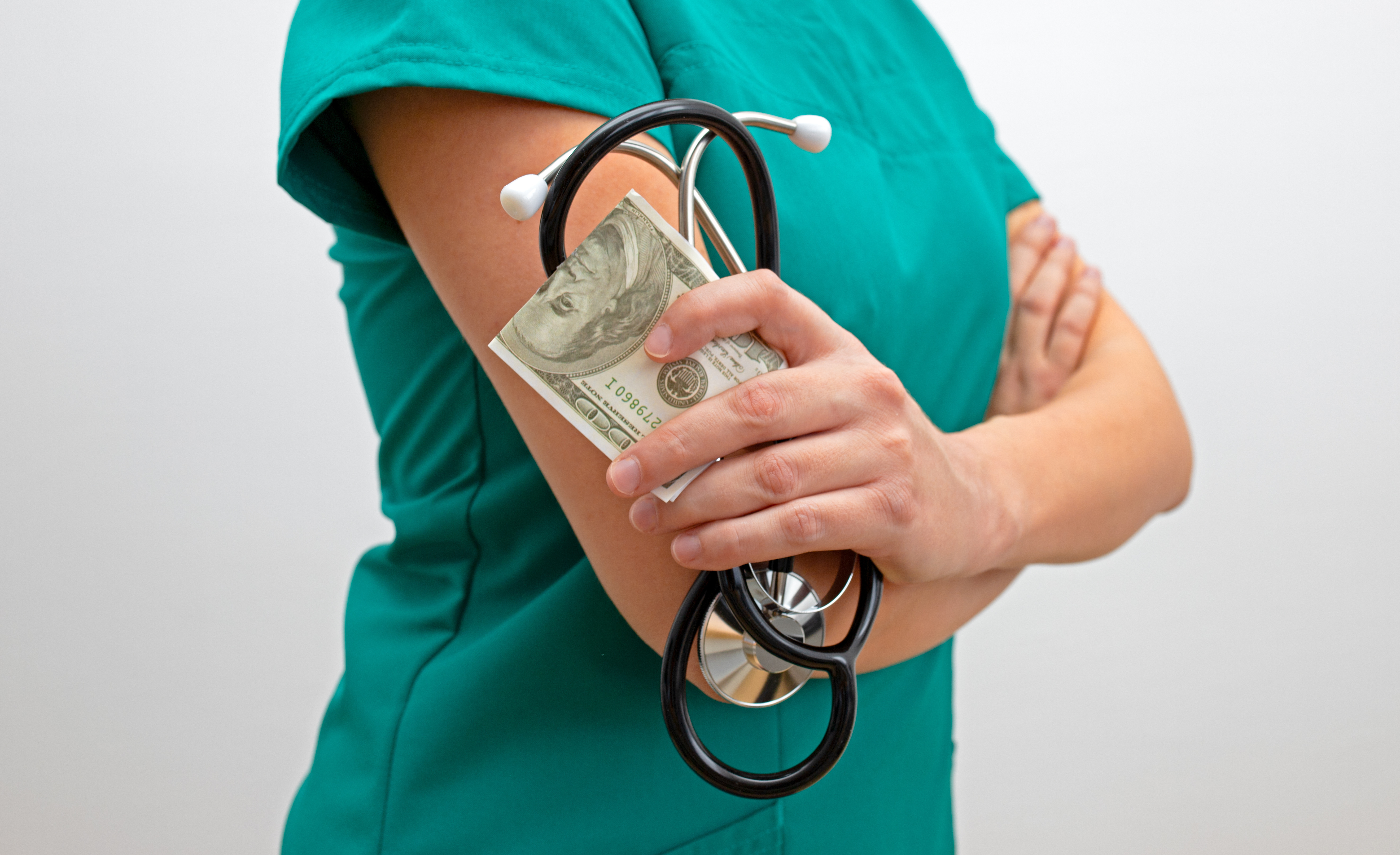 A registered nurse holding a stethoscope and cash, representing ShiftMed’s RN referral bonus paid through payroll.