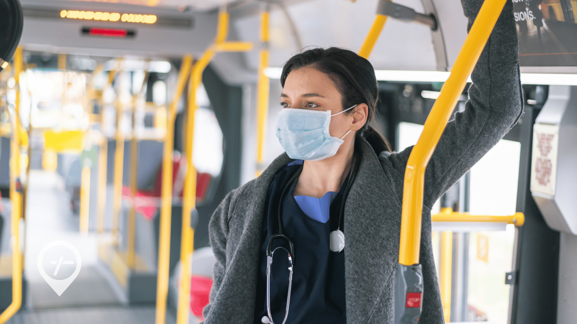 A nurse wearing a mask stares out the window as she commutes to work by bus.