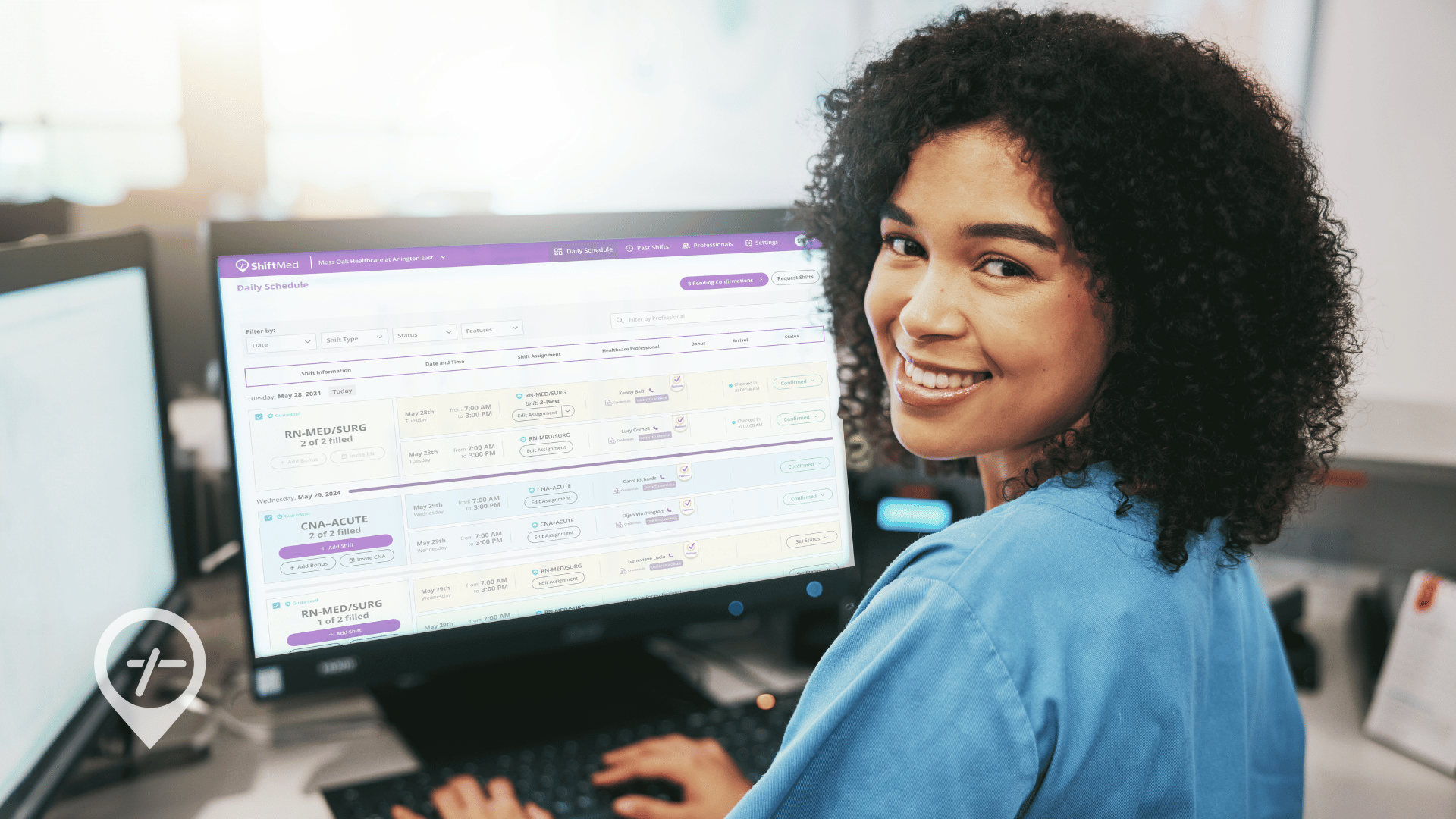 A nurse is sitting at a desk and smiling at the camera with ShiftMed's workforce management system showing up on the computer screen.