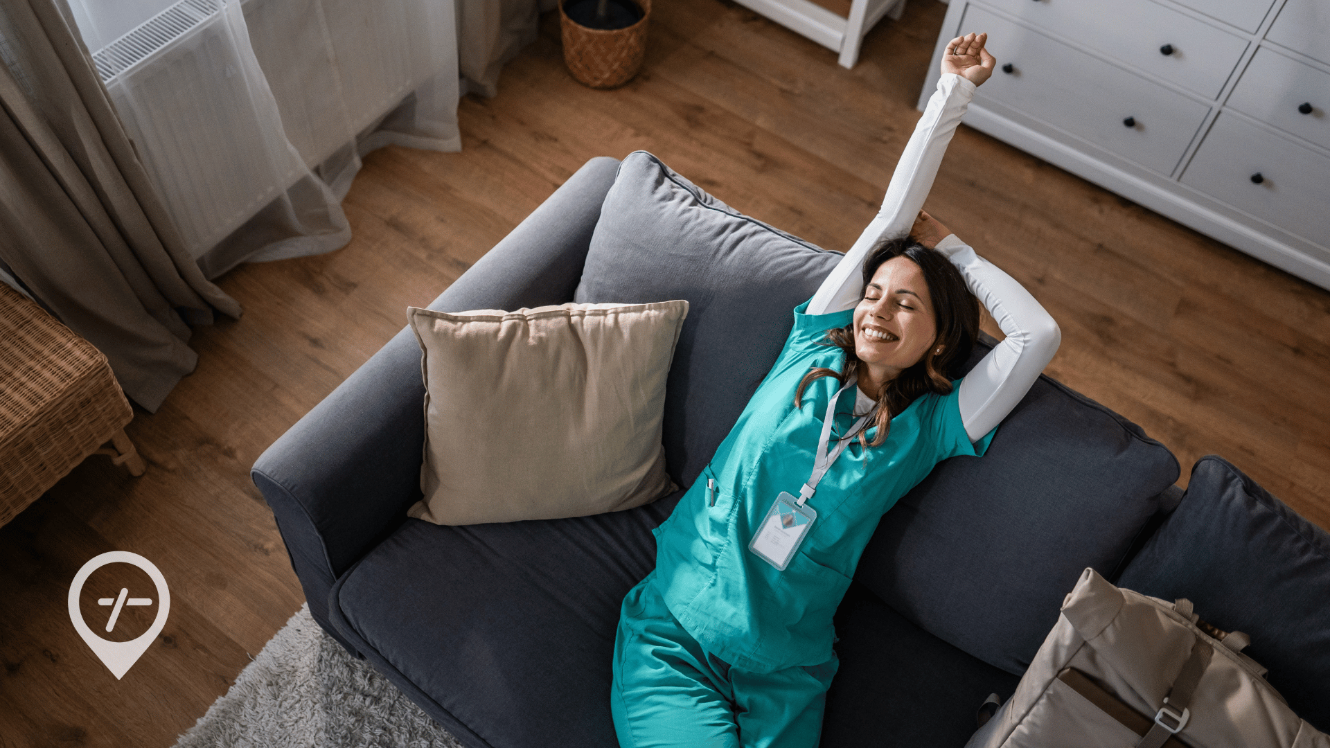 A nurse relaxes on her couch, smiling, embodying the power of self-care and taking a moment to recharge.