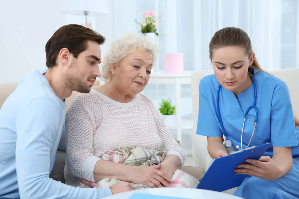 Family nurse practitioner sitting with patient and family member