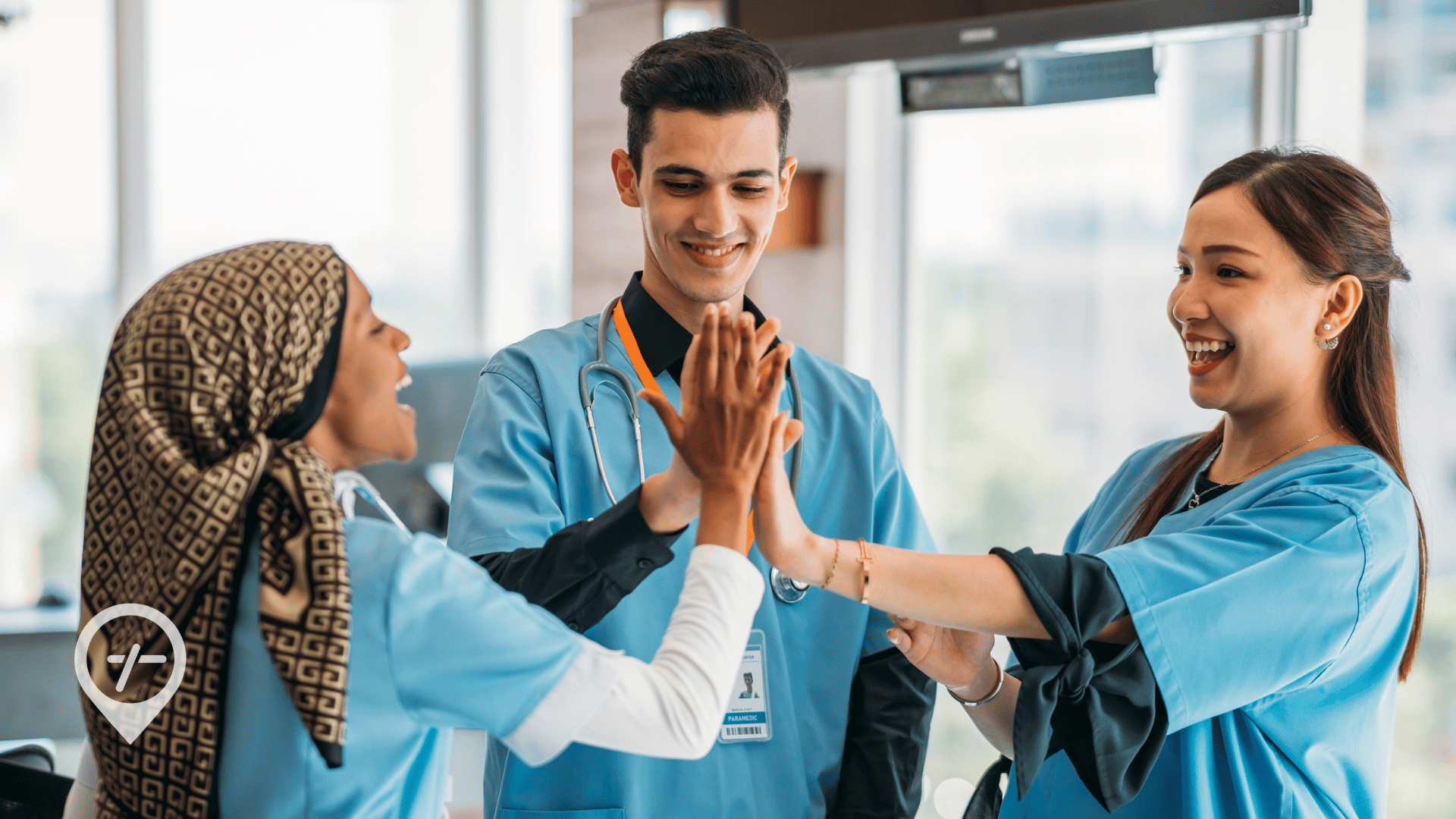 Three nurses high-fiving each other in a hospital hallway.