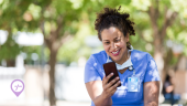 A nurse sitting outside scrolling through her phone looking for flexible nursing shifts.  