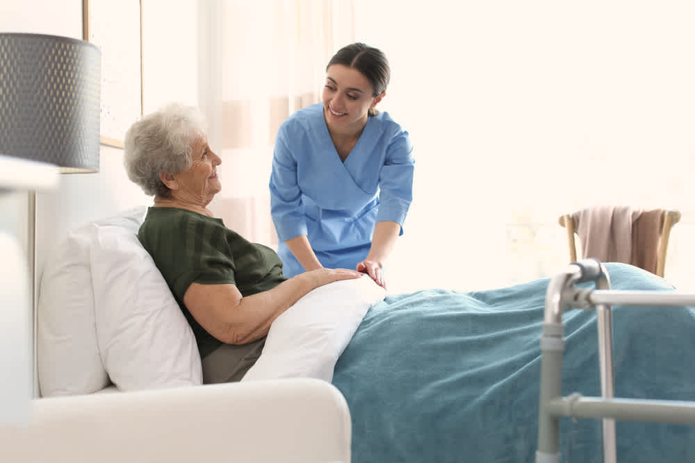 Hospice nurse standing over an older patient