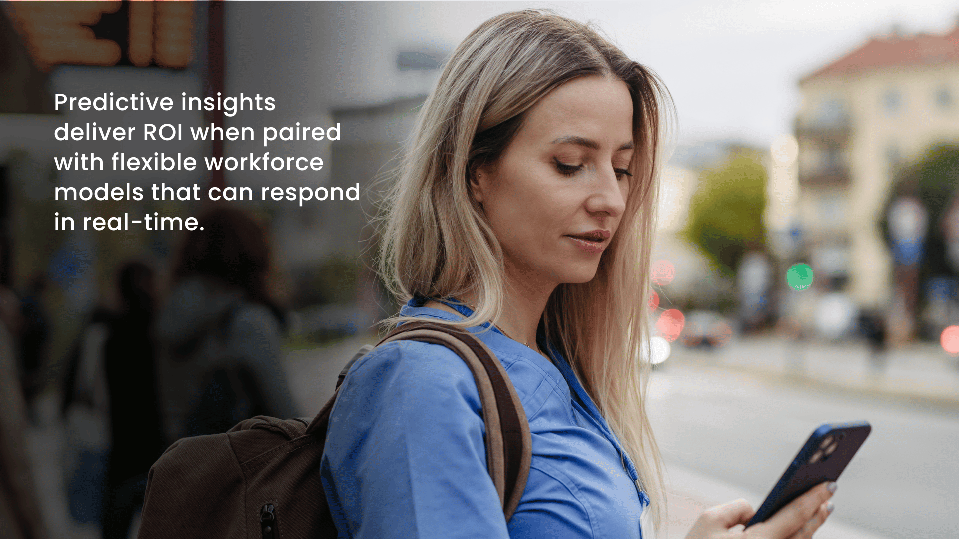 Nurse checking her phone on a city street, representing real-time predictive insights and flexible workforce models in healthcare