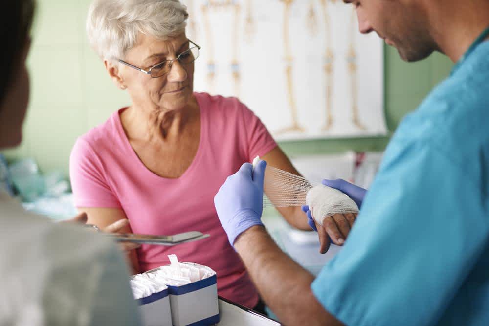 Nurse technician bandaging patient's hand