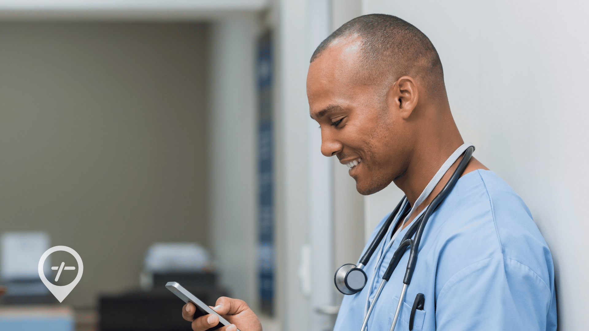 A nurse stands in a hospital hallway looking at the ShiftMed app on his phone to see what open shifts he can claim.